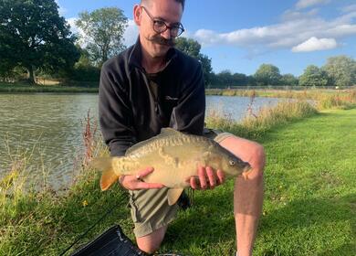 Carp fishing lake at Herefordshire caravan park. Carp and angler photo